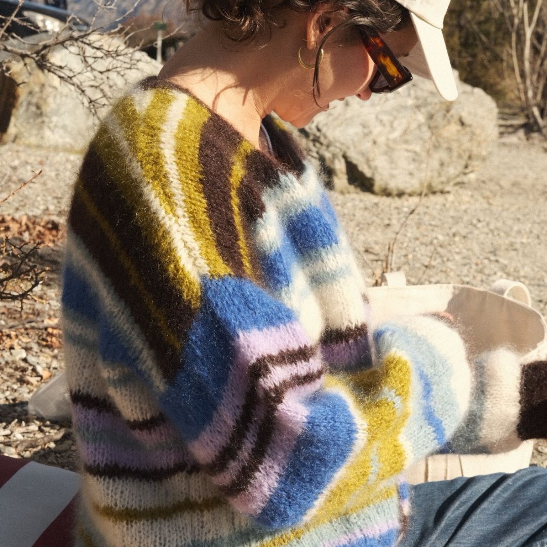 Person wearing a colorful sweater with abstract pattern outdoors.