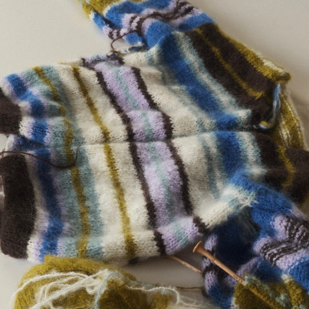 Knitted multicolored socks with yarn and needles on a light background