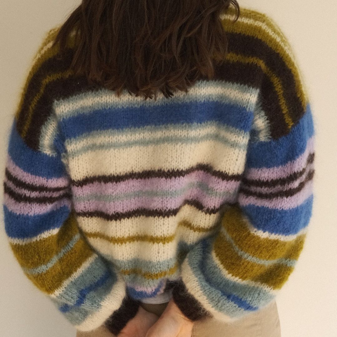 Multicolored striped sweater worn by a person on a plain background