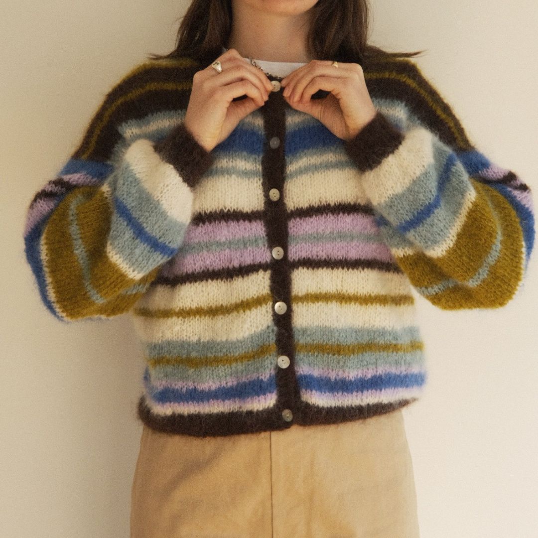 Person wearing a multicolored striped cardigan against a plain background