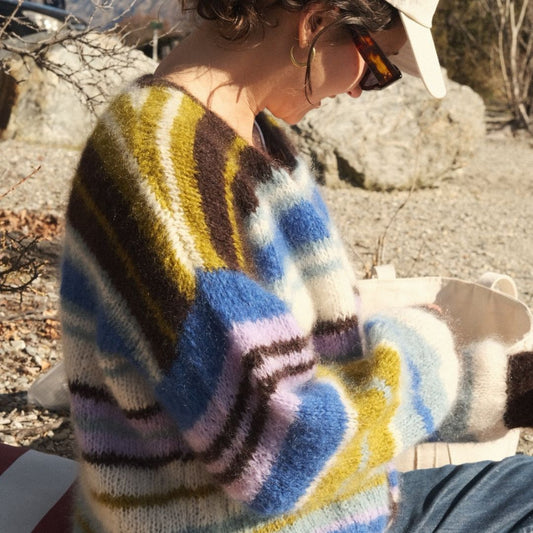 Person wearing a colorful sweater with abstract pattern outdoors.