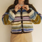 Person wearing a multicolored striped cardigan against a plain background