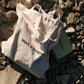 White tote bag with 'Work in Progress' text on a rocky surface